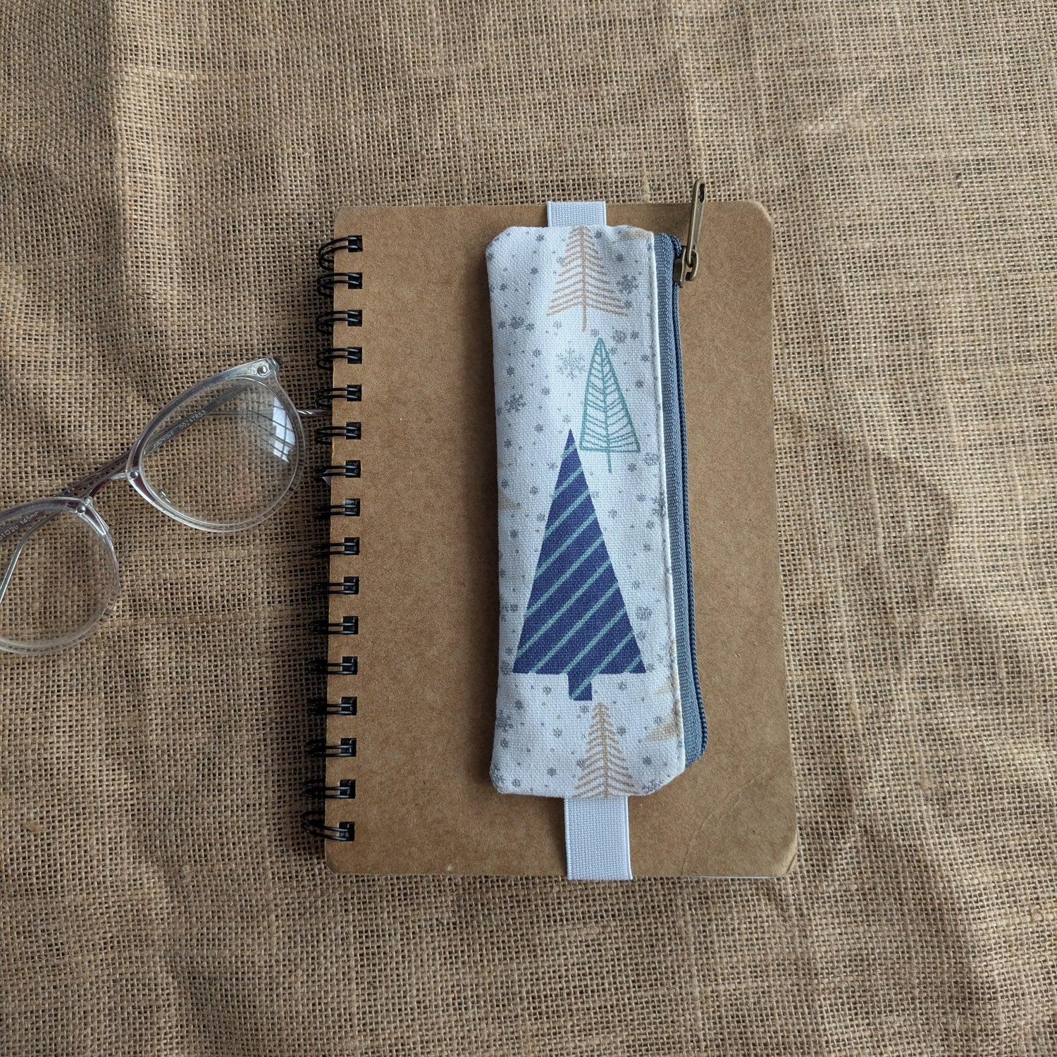 Notebook with a geometric design on a textured surface, it haas an attachable pen sleeve made in fabric