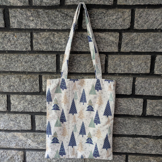 Tote bag with tree pattern hanging against a brick wall