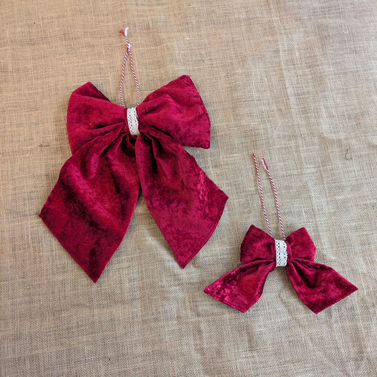 Two red velvet bows with rhinestones on a beige fabric background