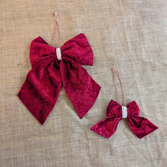 Two red velvet bows with rhinestones on a beige fabric background