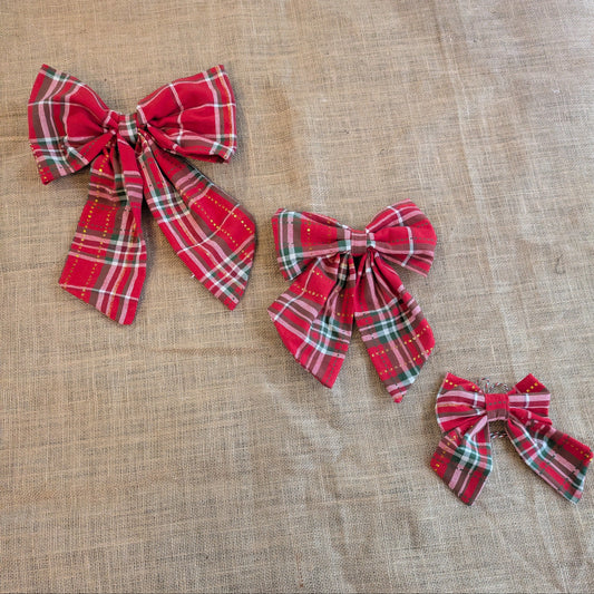 Three red plaid bows on a textured beige background