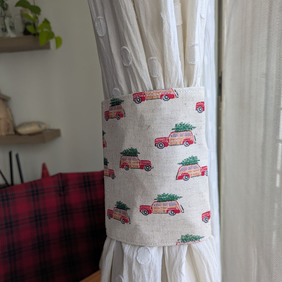 Curtain tieback with vintage car and Christmas tree design attached to a white curtain.