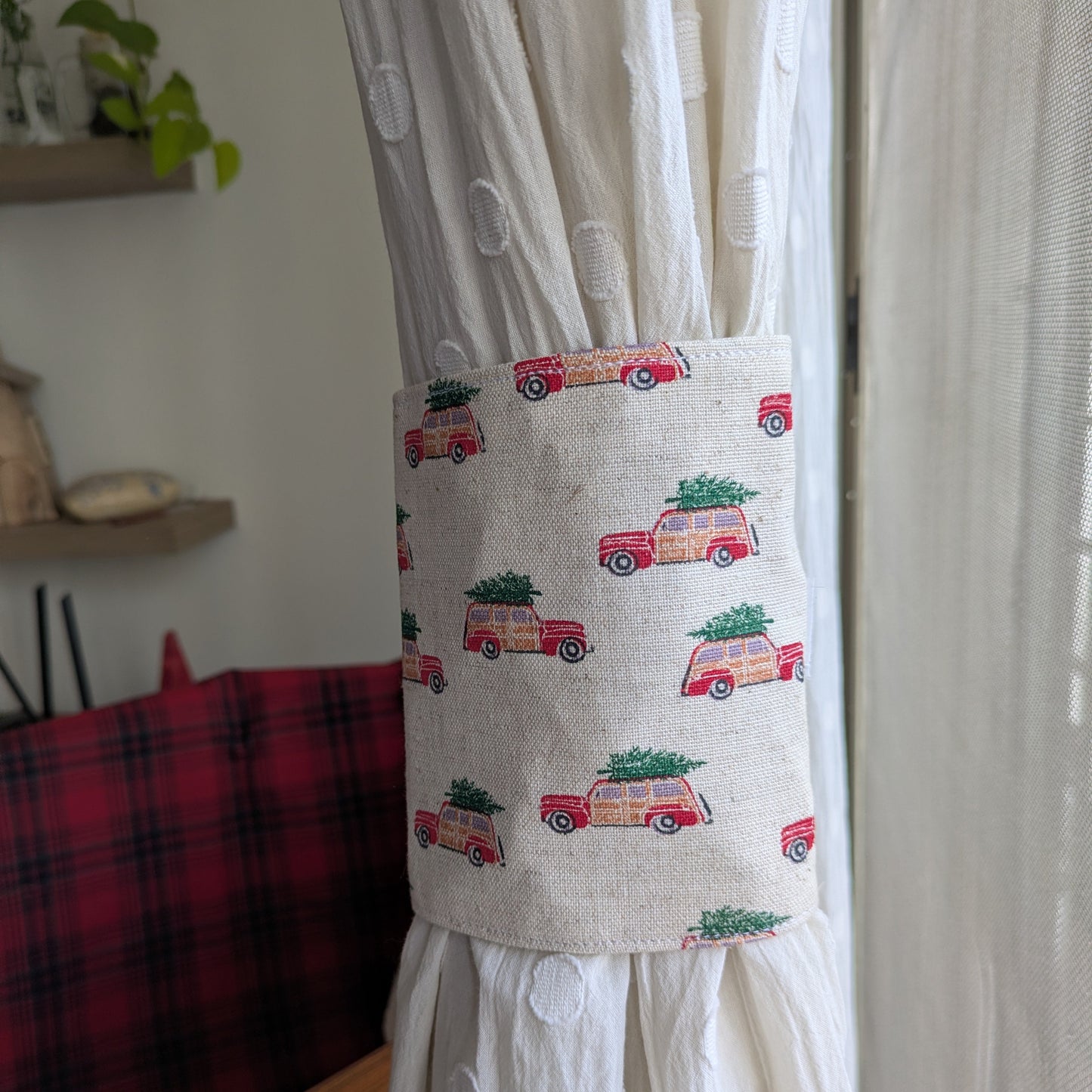 Curtain tieback with vintage car and Christmas tree design attached to a white curtain.