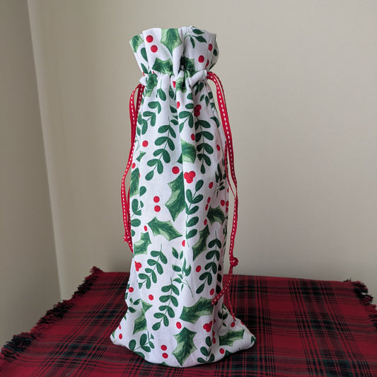 Decorative drawstring bag with holly design on a red plaid surface