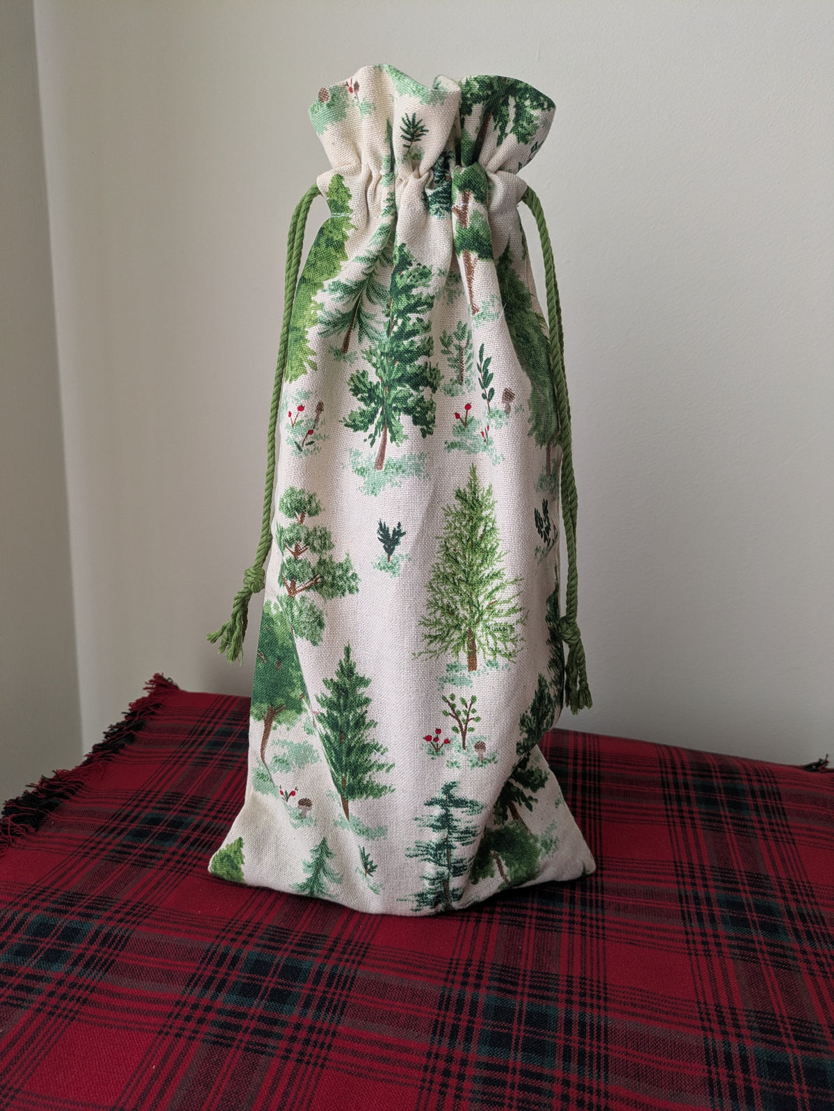 Drawstring bag with Christmas tree pattern on a red plaid surface