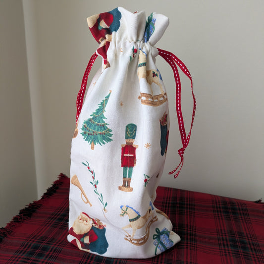 Decorative drawstring bag with Christmas-themed designs on a red plaid surface.