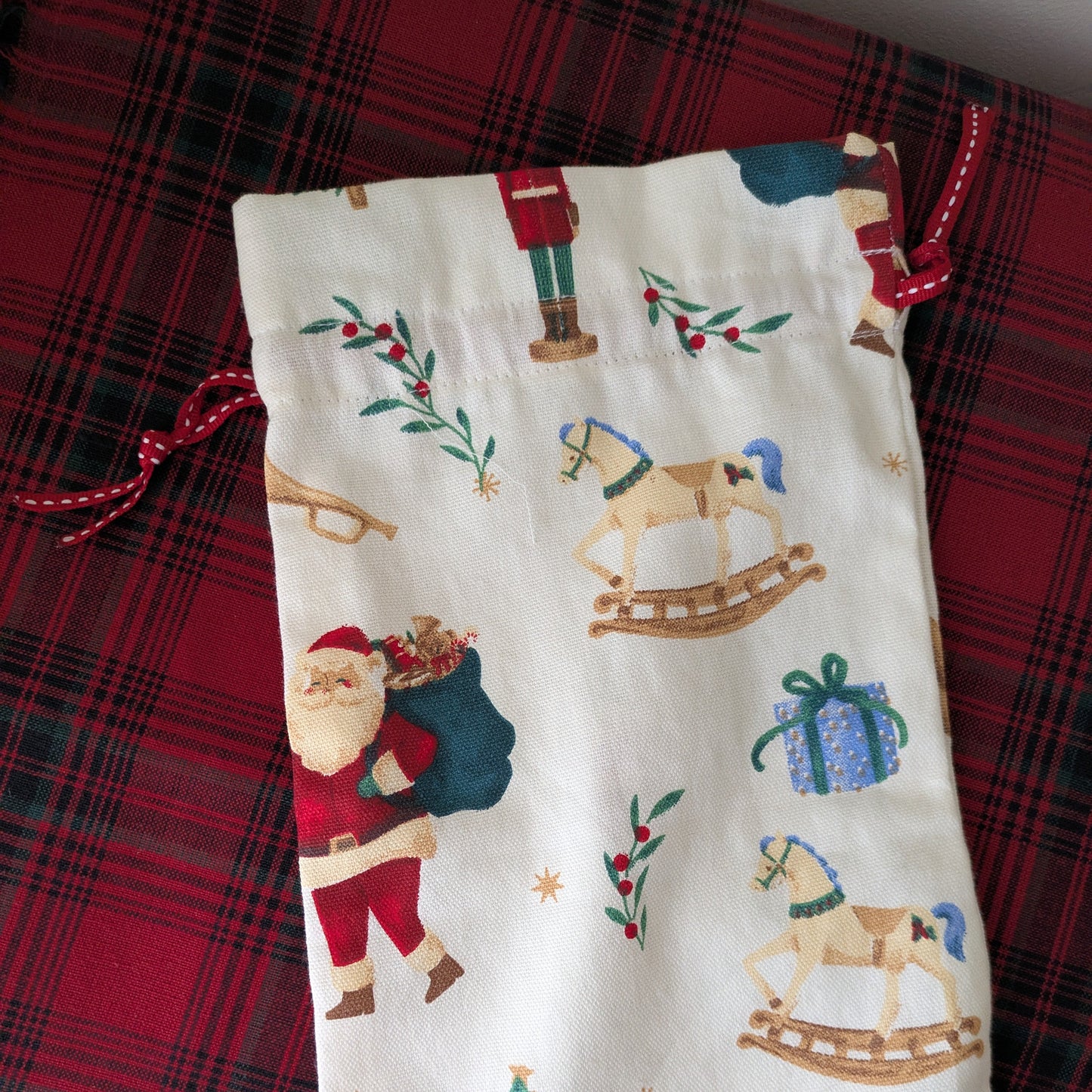 Fabric pouch with Christmas-themed design on a red plaid background