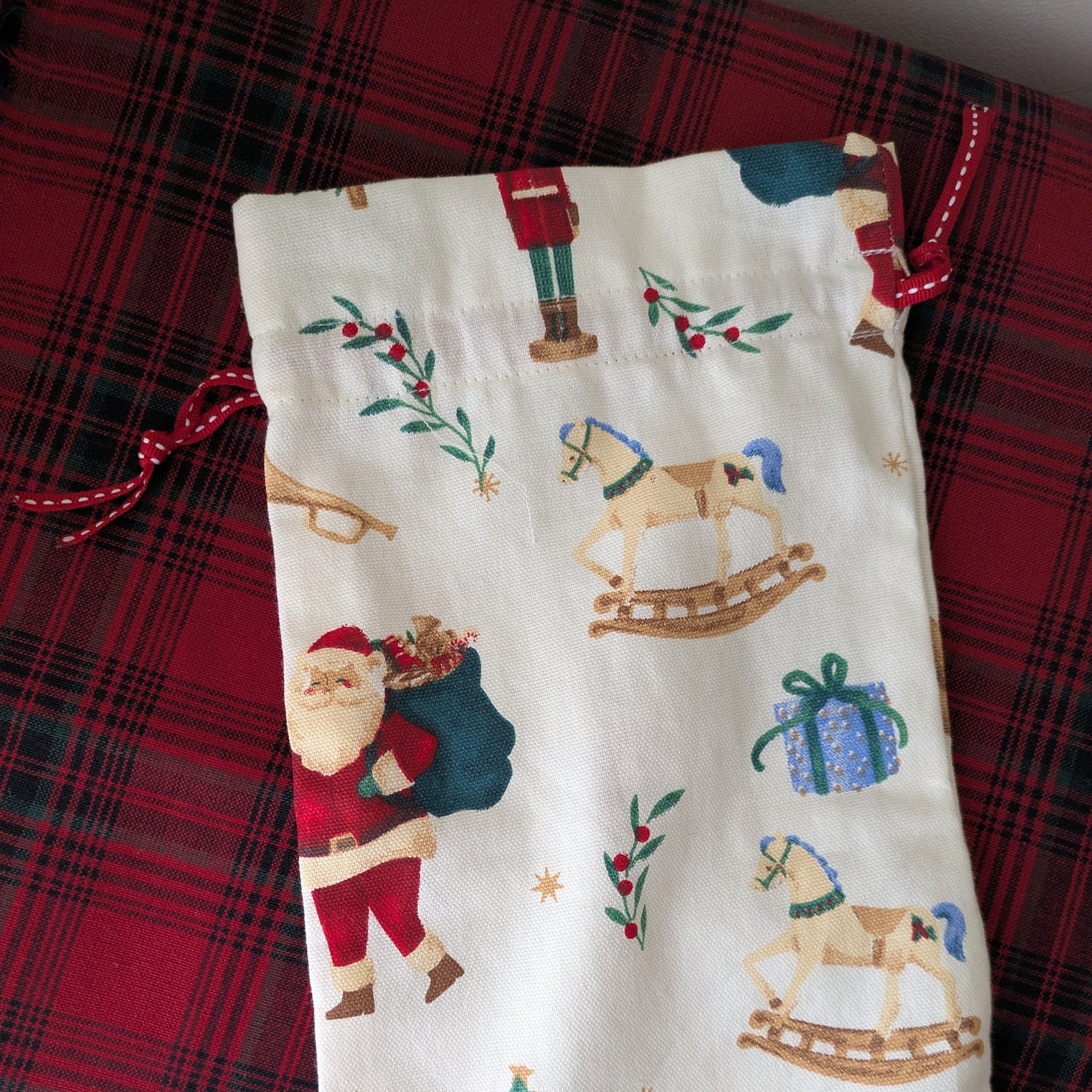Fabric pouch with Christmas-themed design on a red plaid background