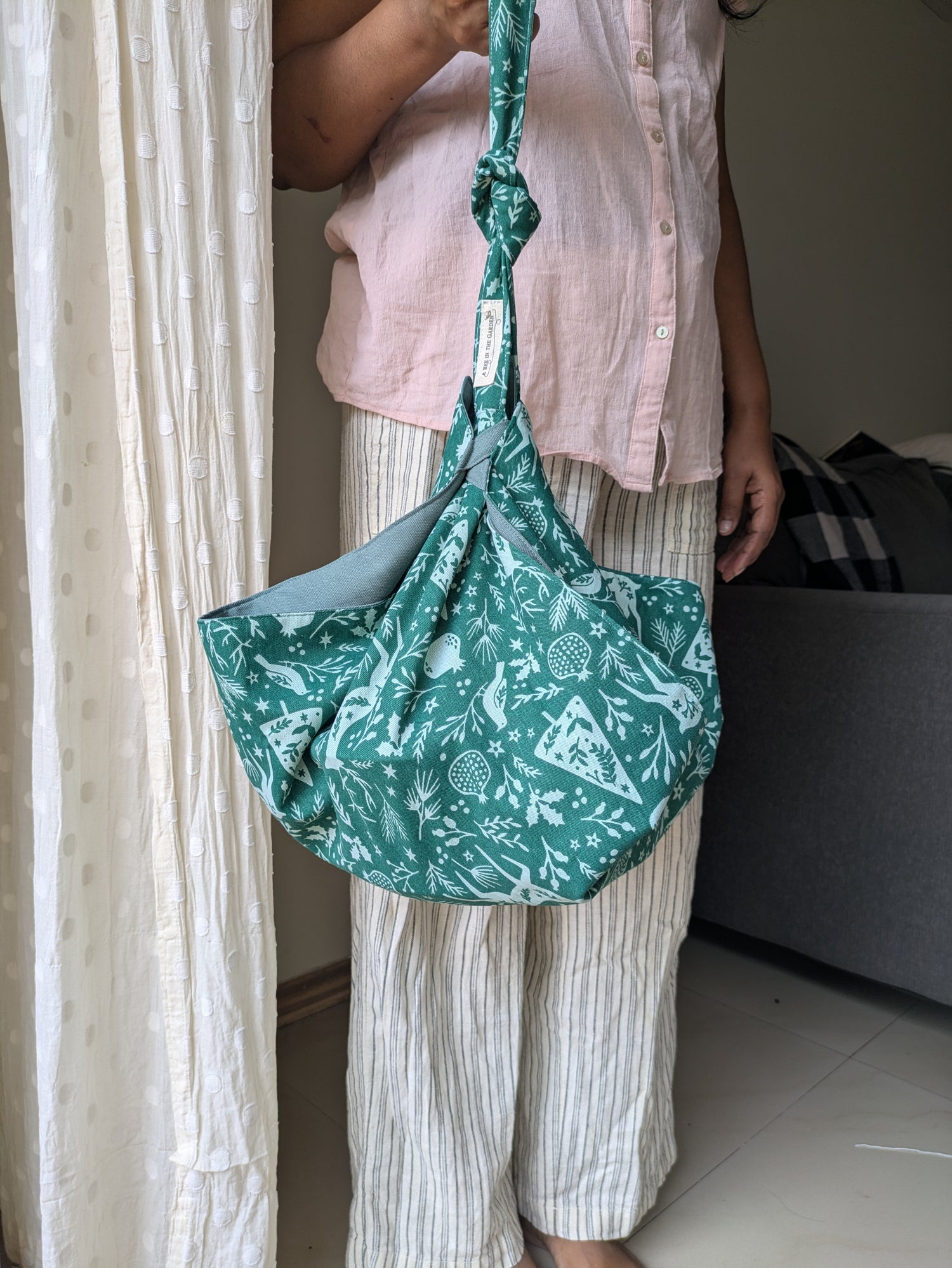 Person holding a green floral-patterned bag indoors