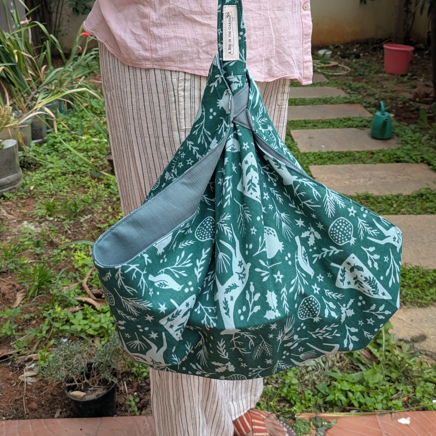 Person holding a green patterned casserole carrier outdoors