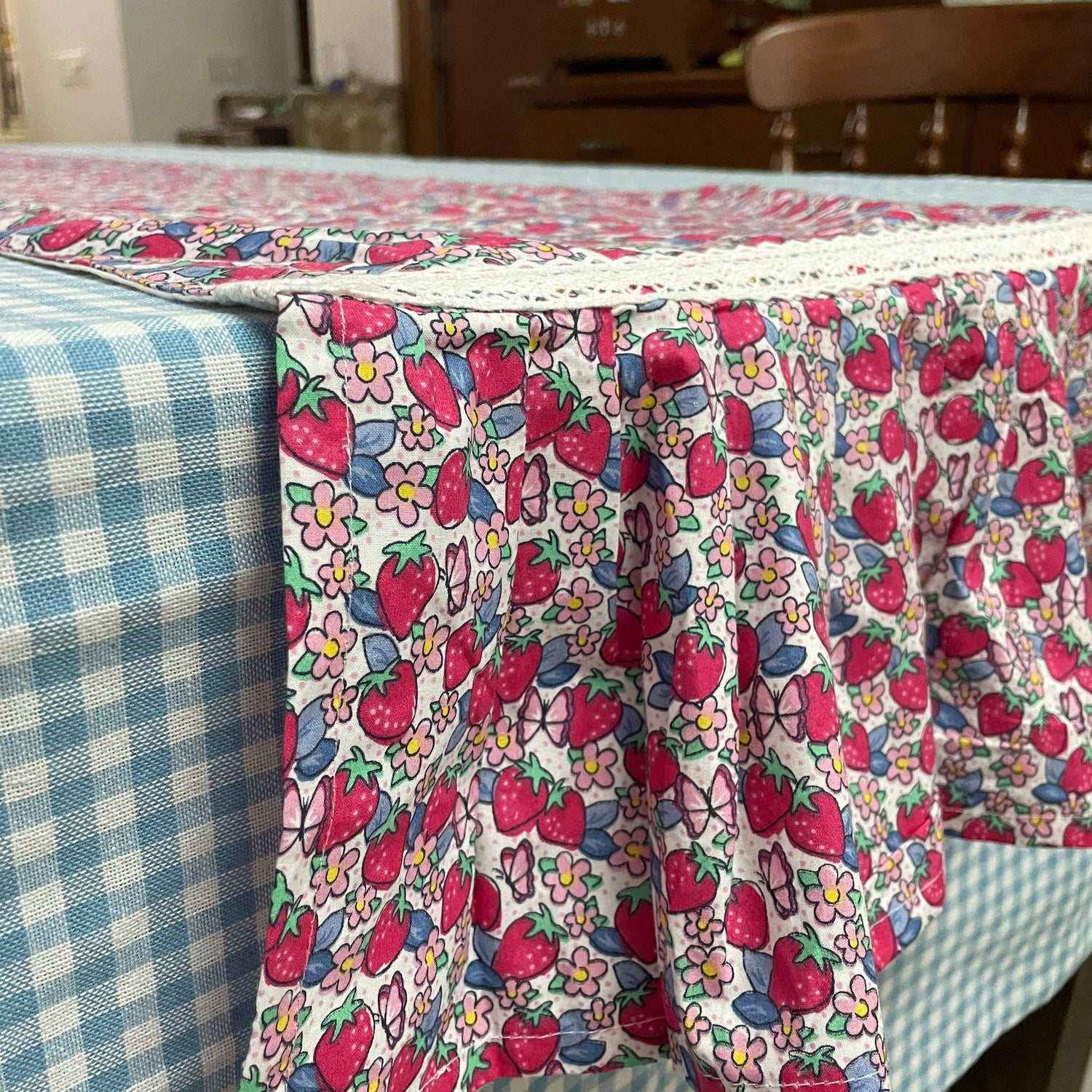 a table runner in summer colours, strawberry garden ditsy print all over and with frilly edges.